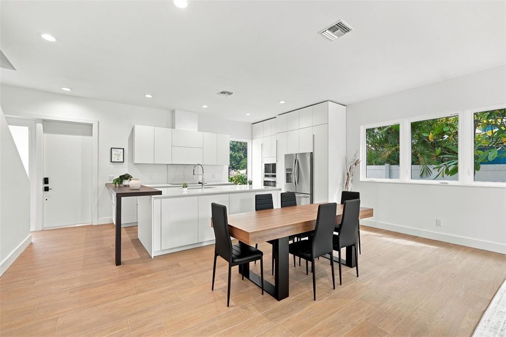A modern kitchen with a white island and stainless steel appliances overlooks a living area — 2516 BROWNING STREET, SARASOTA, FL