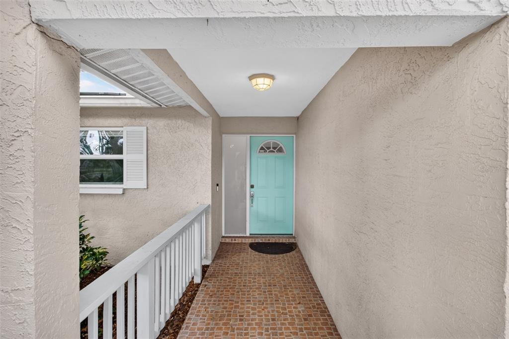A covered entryway features a light blue front door, white railing, and tiled flooring — 12499 82ND TERRACE, SEMINOLE, FL