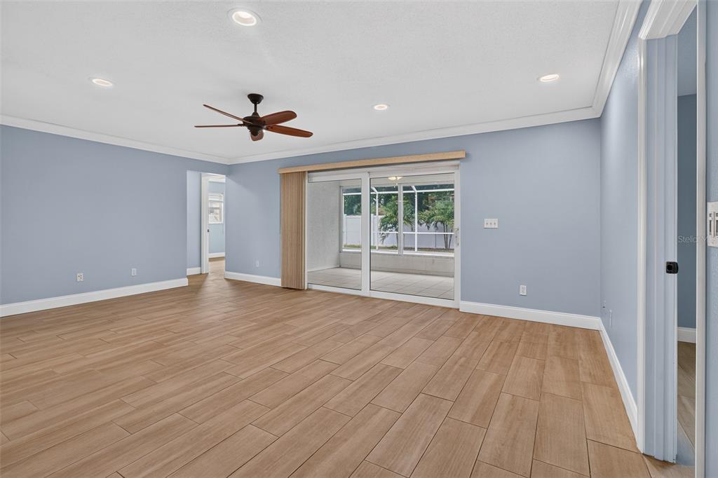 A spacious living room features light blue walls, wood-look tile flooring, and sliding glass doors — 12499 82ND TERRACE, SEMINOLE, FL