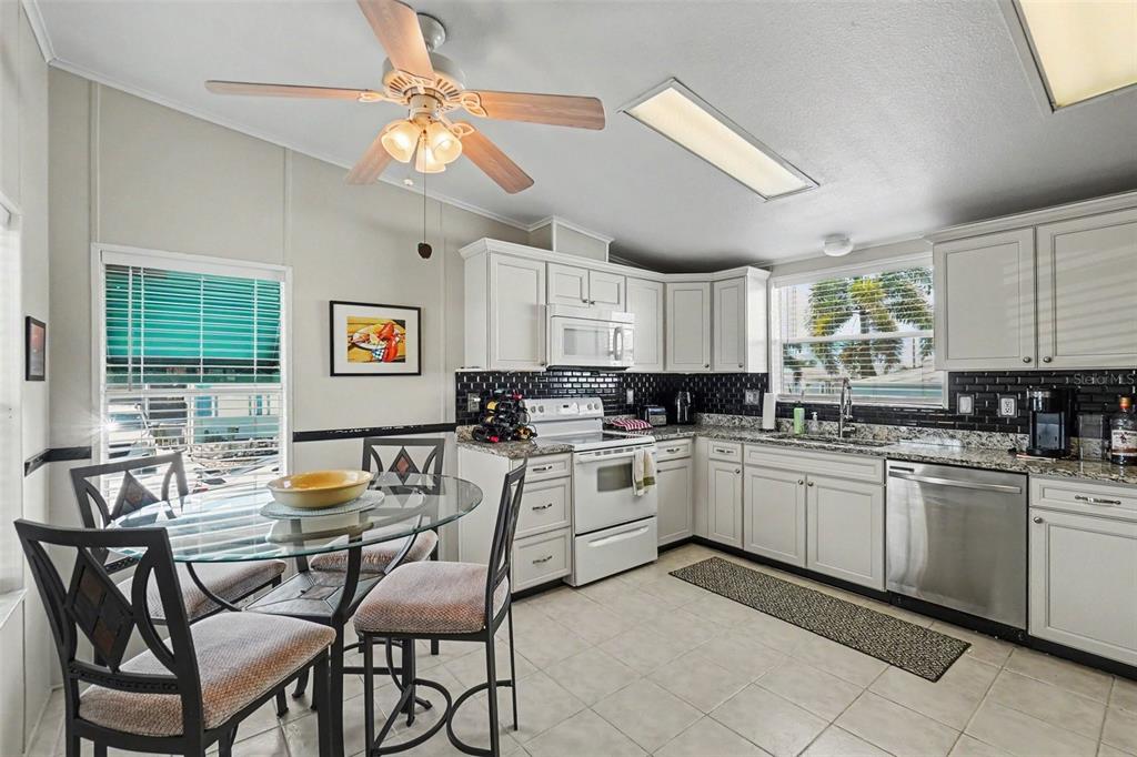A kitchen features white cabinets, stainless steel appliances, a glass dining table, and tile flooring — 226 BIMINI DRIVE, PALMETTO, FL