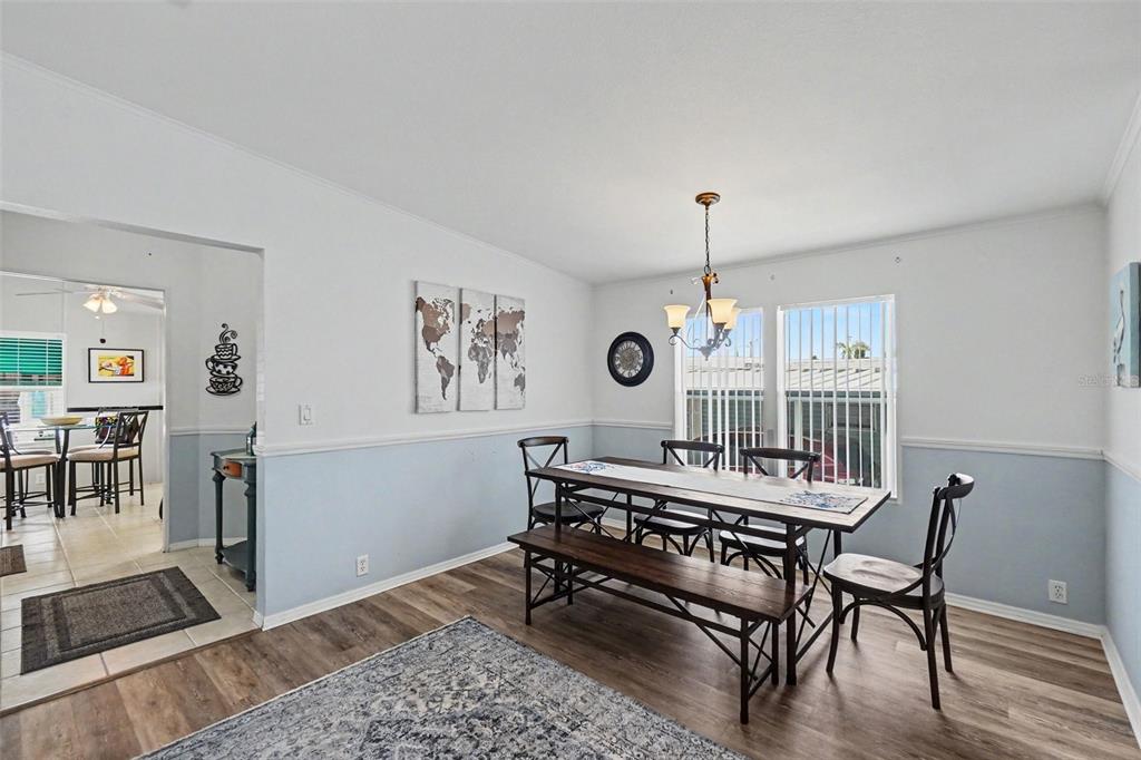 A dining room features a wooden table with a bench, chairs, and a world map wall art — 226 BIMINI DRIVE, PALMETTO, FL