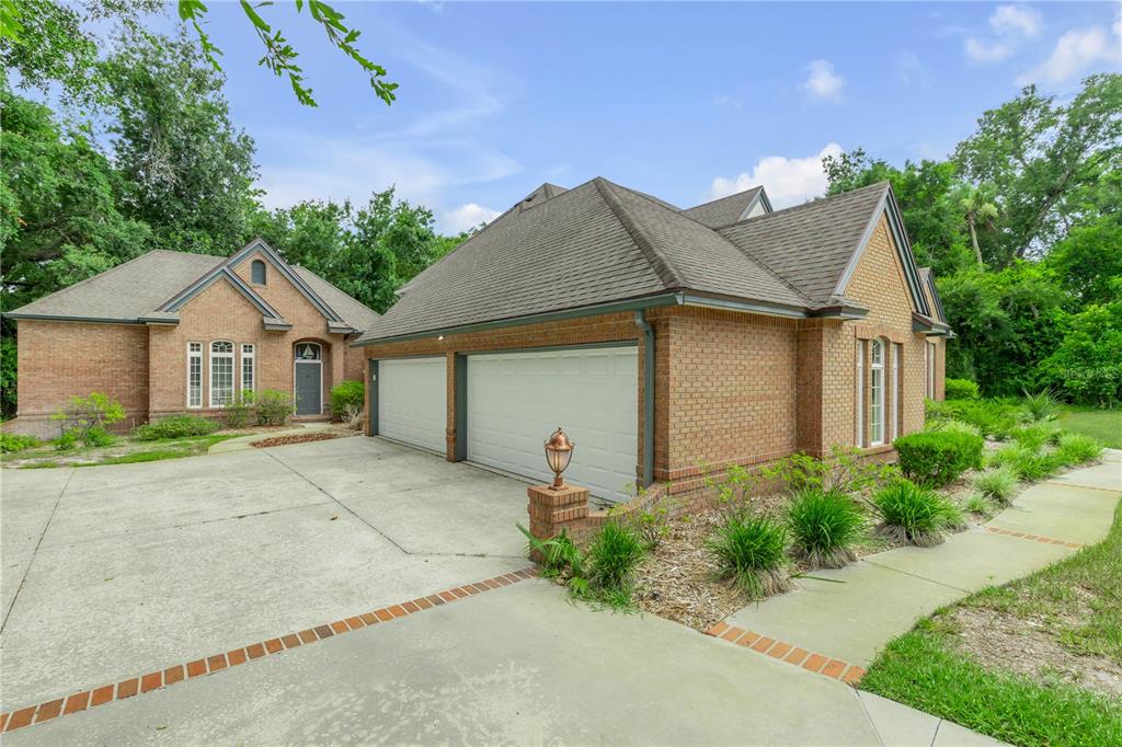 A brick house with a two-car garage and a concrete driveway surrounded by trees — 18 LOST CREEK LANE, ORMOND BEACH, FL