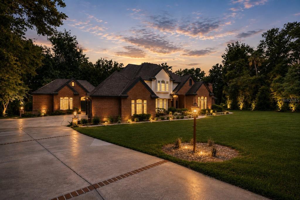 A brick house with a large lawn and driveway at sunset — 18 LOST CREEK LANE, ORMOND BEACH, FL