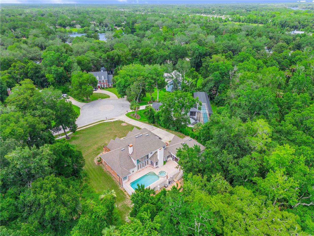 An aerial view of a large house with a swimming pool surrounded by dense trees — 18 LOST CREEK LANE, ORMOND BEACH, FL