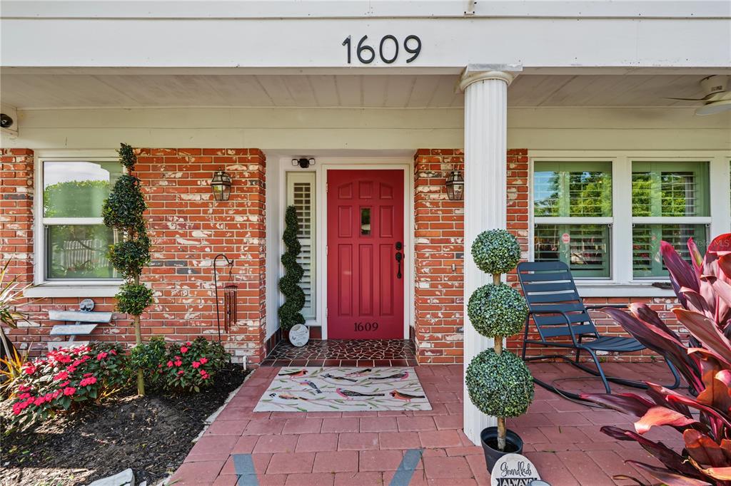 A red front door is centered on a brick porch with a white column — 1609 MELODIE DRIVE, BRANDON, FL