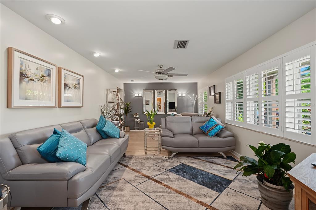 A living room features two gray leather sofas, a geometric rug, and plantation shutters — 1609 MELODIE DRIVE, BRANDON, FL