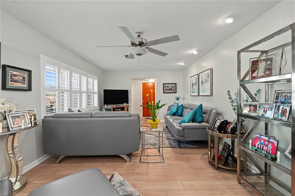 A living room features gray leather sofas, wood-look flooring, and a ceiling fan — 1609 MELODIE DRIVE, BRANDON, FL