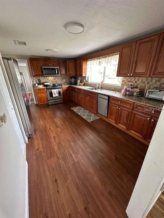 A kitchen features wood cabinets, stainless steel appliances, and wood-look flooring — 1509 TATE STREET, COCOA, FL