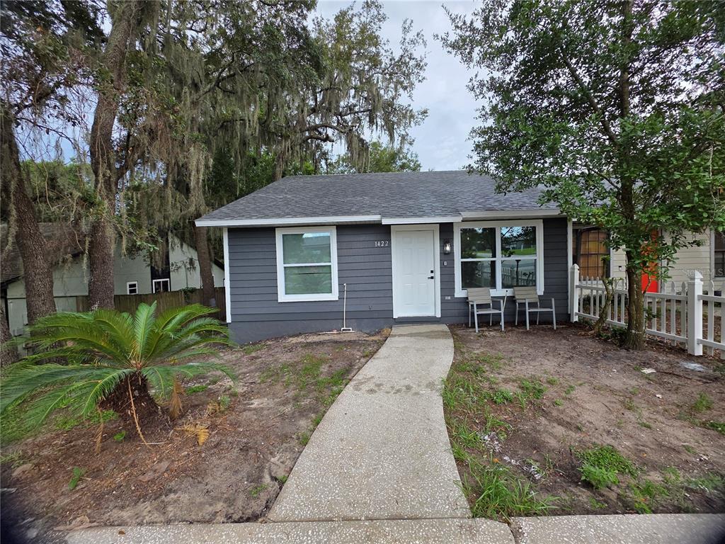 A gray-sided house with a white door, concrete walkway, and a large palm plant — 1422 PLYMOUTH AVENUE, MOUNT DORA, FL