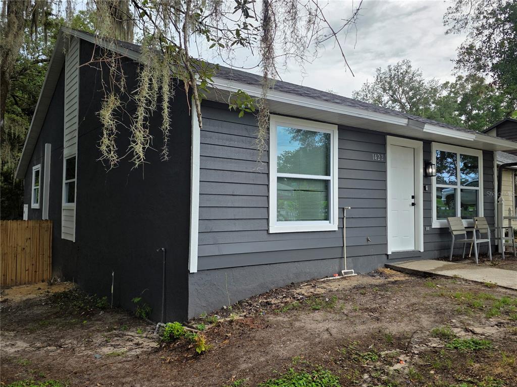 A gray house exterior features horizontal siding, white trim, and a white front door — 1422 PLYMOUTH AVENUE, MOUNT DORA, FL