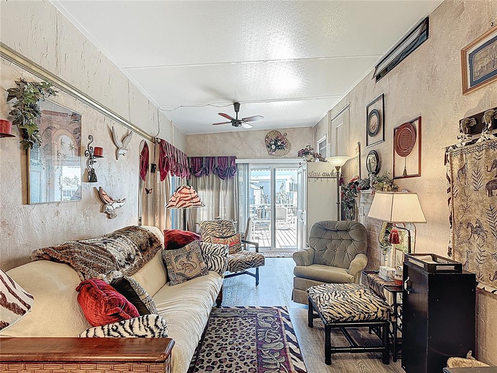 A living room features a sofa, patterned textiles, wall decor, and a sliding glass door — 9000 US HWY 192 UNIT 214, CLERMONT, FL