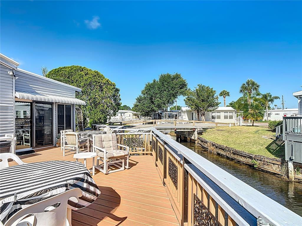 A wooden deck overlooks a canal with outdoor seating and a striped table cover — 9000 US HWY 192 UNIT 214, CLERMONT, FL