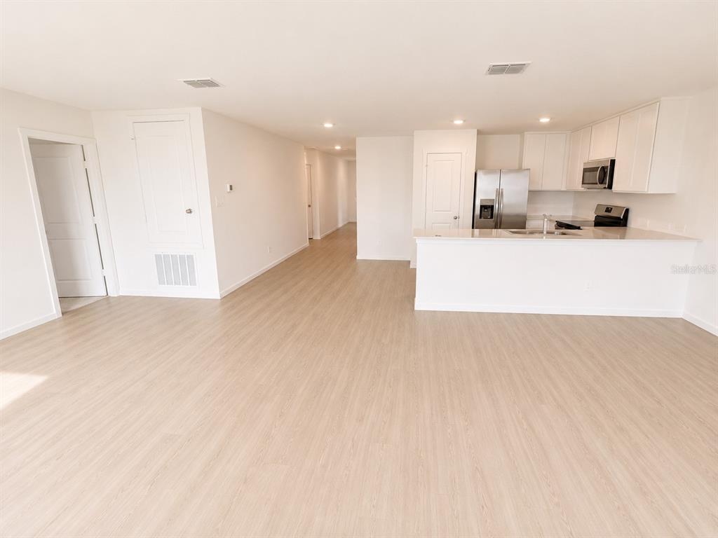 An open-concept living area features light wood-look flooring and a kitchen with white cabinetry — 3171 TOTEM ROAD, EAGLE LAKE, FL