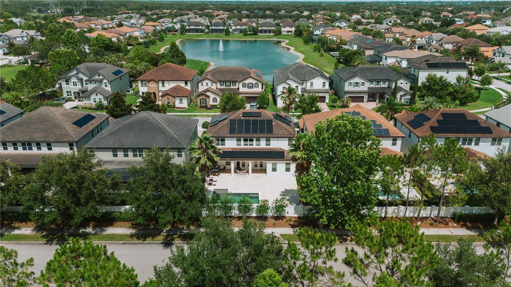 An aerial view shows a suburban neighborhood with houses, a central pond, and solar panels — 11768 HAMPSTEAD STREET, WINDERMERE, FL