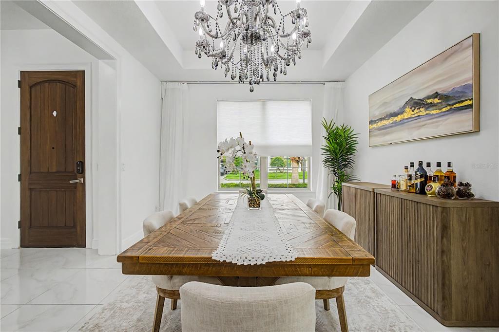A dining room features a large wooden table, a crystal chandelier, and a sideboard — 11768 HAMPSTEAD STREET, WINDERMERE, FL