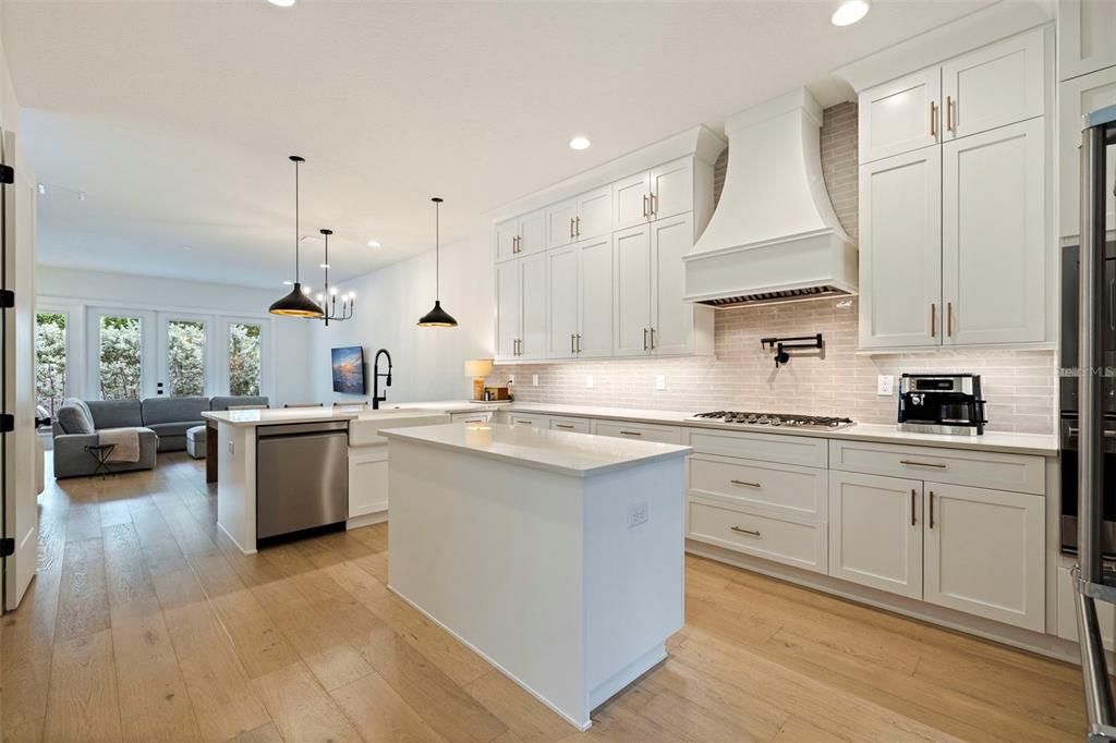 A modern kitchen features white cabinetry, a central island, stainless steel appliances, and wood flooring — 410 S HABANA AVENUE UNIT 1, TAMPA, FL