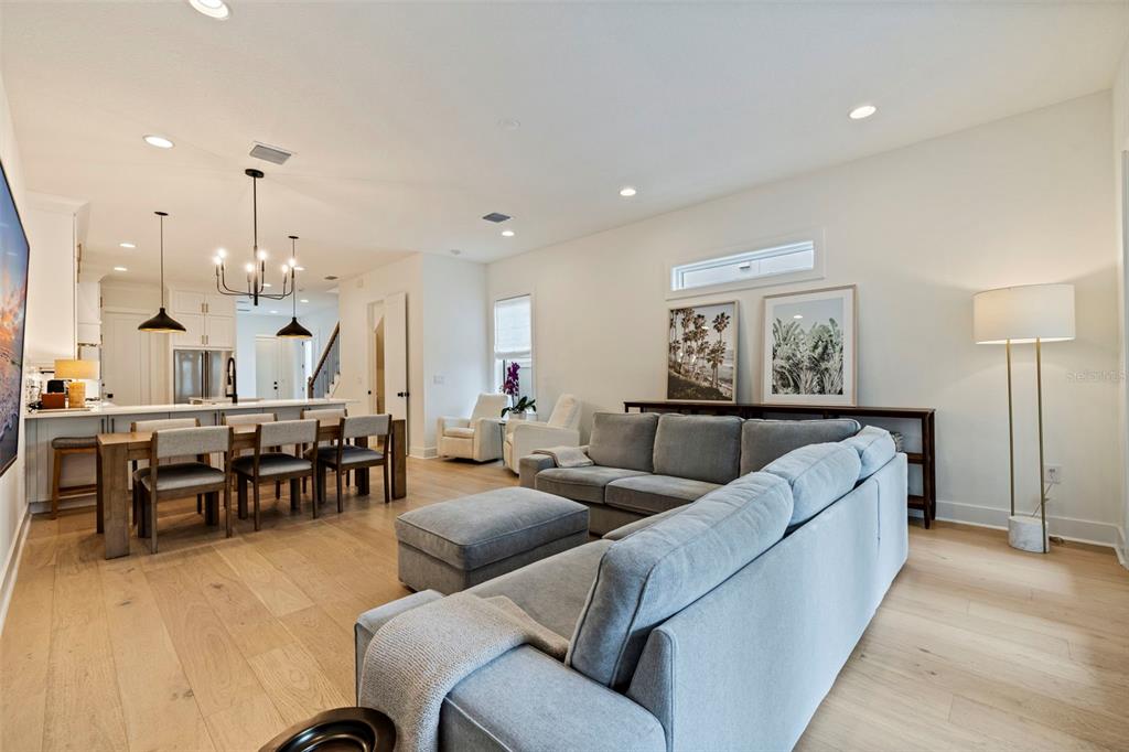 An open-concept living and dining area features light wood floors, a gray sectional, and kitchen — 410 S HABANA AVENUE UNIT 1, TAMPA, FL