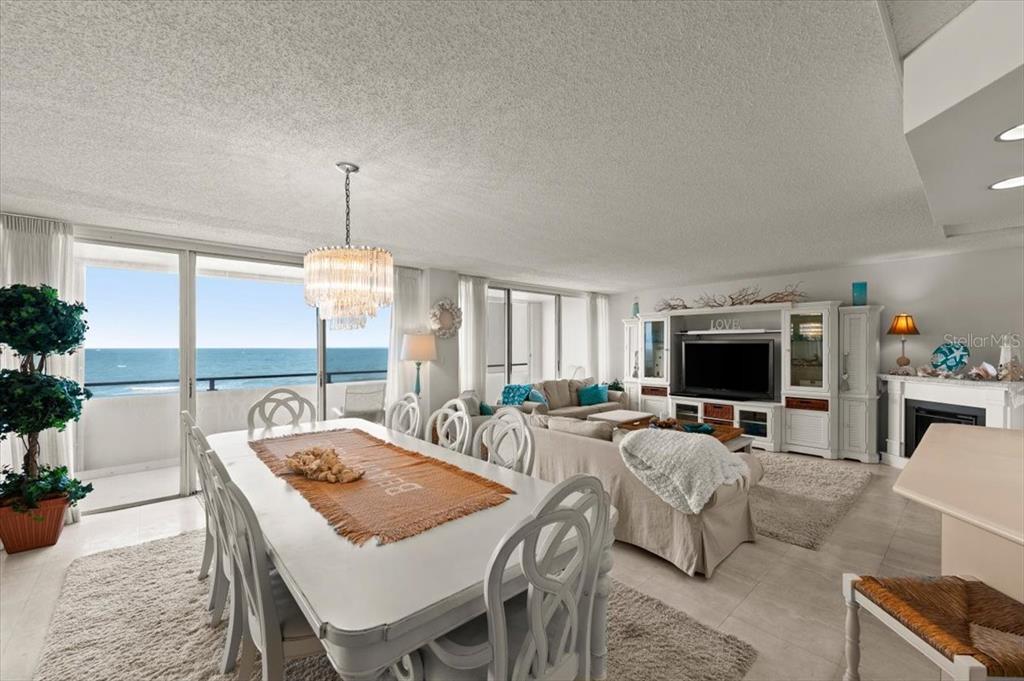 A bright dining and living area features a white table, chandelier, and ocean views — 901 S ATLANTIC AVENUE UNIT PH3, ORMOND BEACH, FL