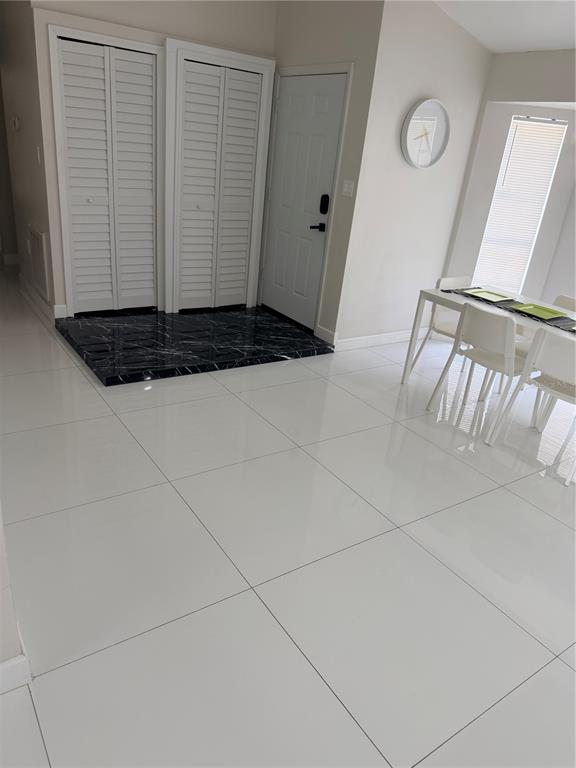 A living room with a black sectional sofa, white tile floors, and a large wall mirror — 310 SILK OAK DRIVE, KISSIMMEE, FL