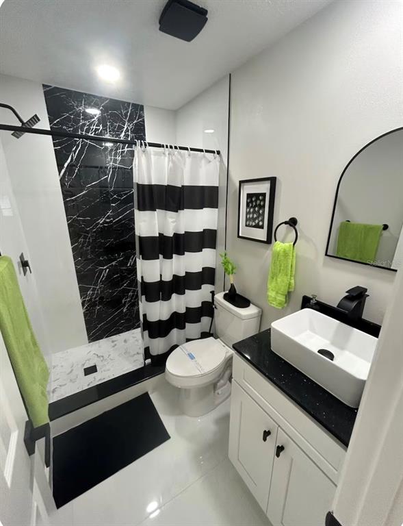 A dining area with white tile floors and a black marble-tiled entryway with closet doors — 310 SILK OAK DRIVE, KISSIMMEE, FL