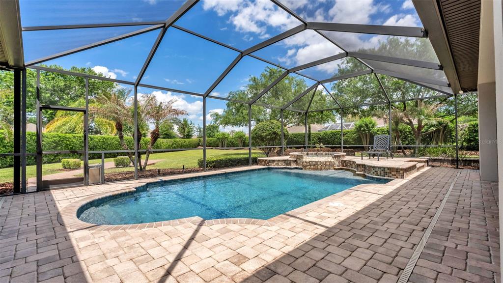 A screened-in patio features a swimming pool, a raised hot tub, and paver decking — 6538 EAGLE VIEW LOOP, LAKELAND, FL