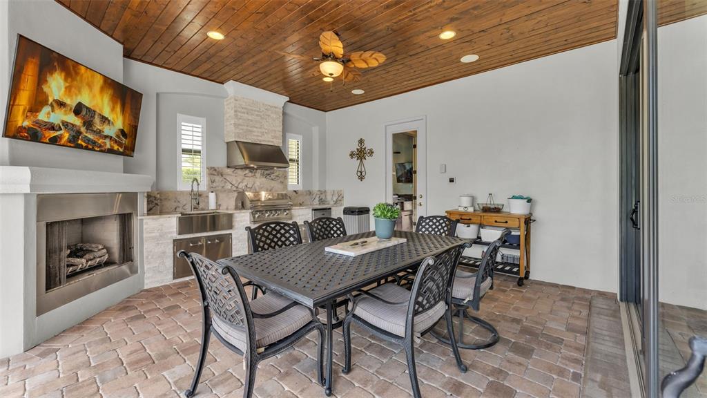 A covered outdoor patio features a dining set, fireplace, built-in grill, and wood-paneled ceiling — 6538 EAGLE VIEW LOOP, LAKELAND, FL