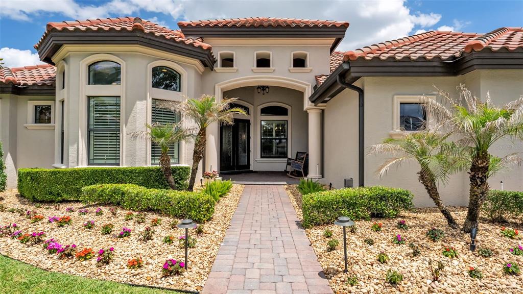 A paved walkway leads to the arched entryway of a house with a tile roof — 6538 EAGLE VIEW LOOP, LAKELAND, FL