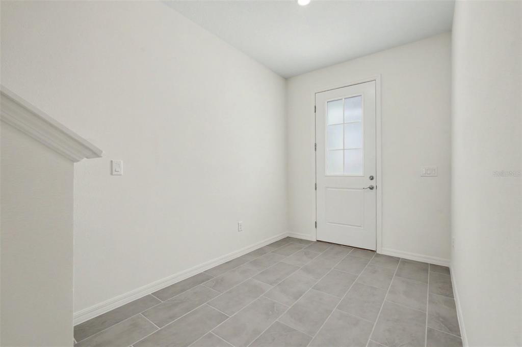 An entryway features gray tile flooring, white walls, and a white door with glass panels — 31799 KESTREL CALLING DRIVE, SAN ANTONIO, FL