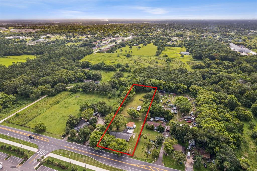 An aerial view shows a rectangular property lot outlined in red along a paved road — 1001 OCOEE APOPKA ROAD, OCOEE, FL