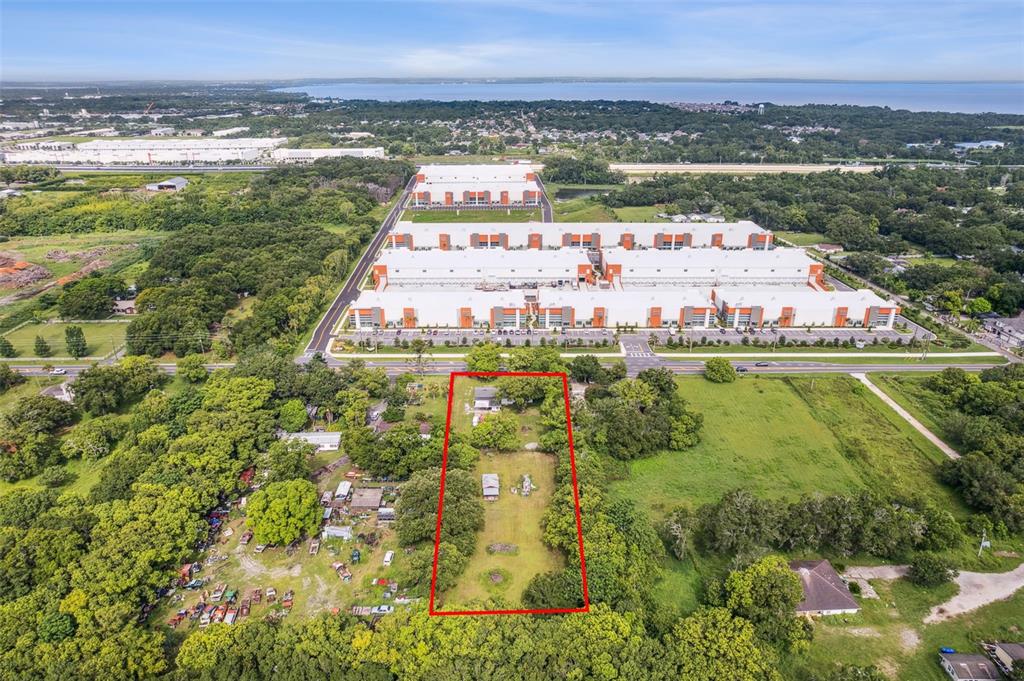 An aerial view shows a rectangular residential lot outlined in red near a large warehouse — 1001 OCOEE APOPKA ROAD, OCOEE, FL