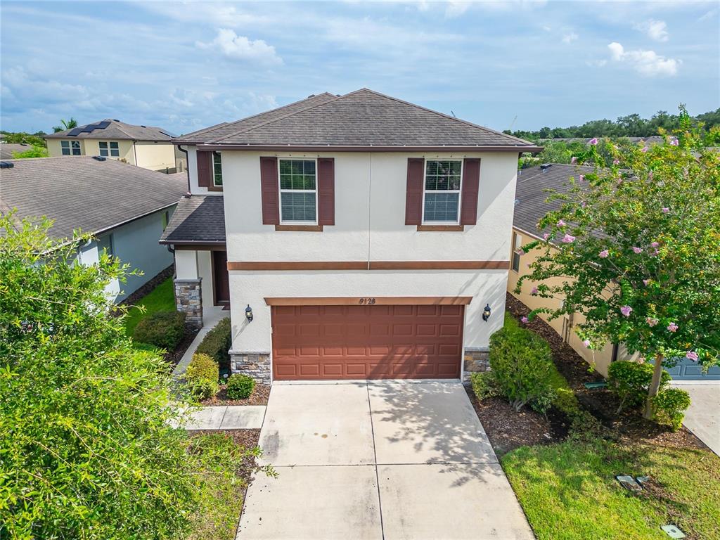 An aerial view of a two-story suburban house with a brown garage and tan stucco — 9128 GRANT LINE LANE, RIVERVIEW, FL