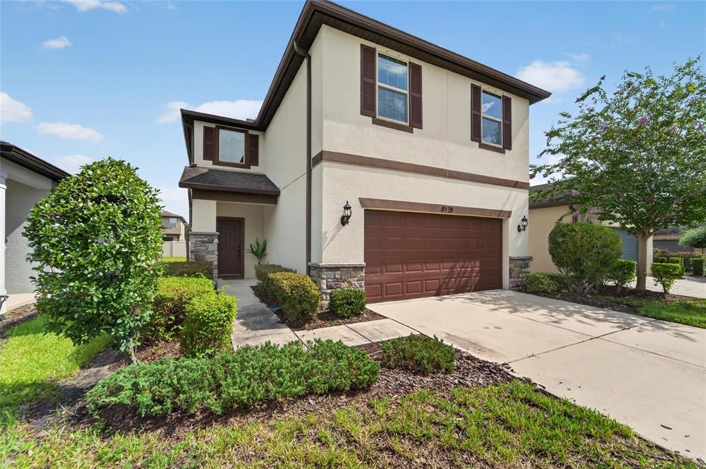 A two-story house with a beige stucco exterior, brown shutters, and a two-car garage — 9128 GRANT LINE LANE, RIVERVIEW, FL