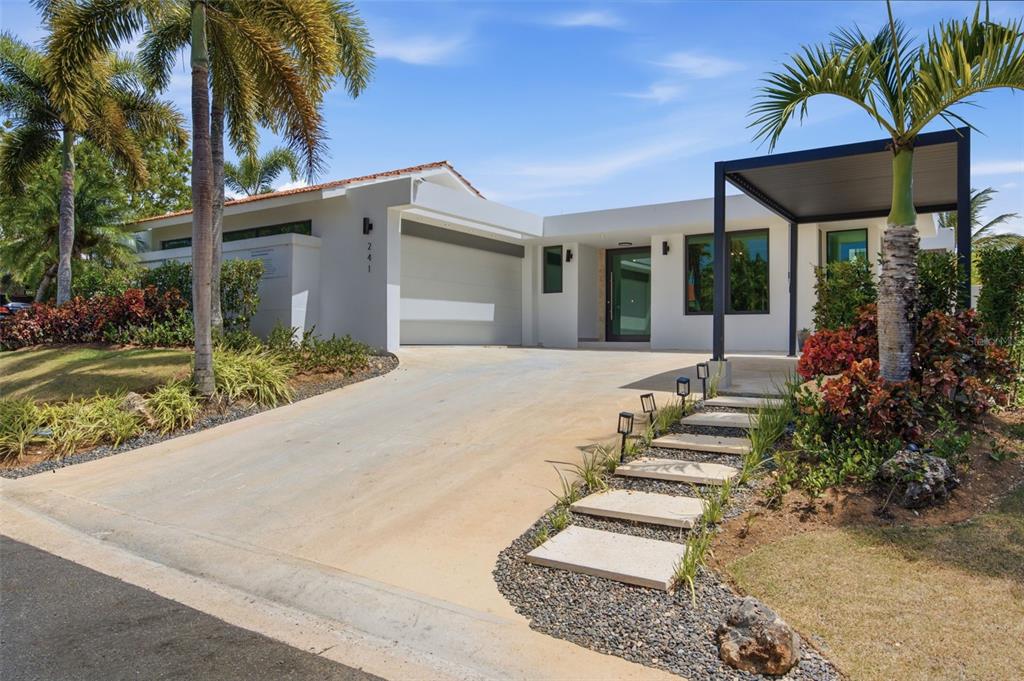A modern open-concept living area features a large kitchen island, gray sofas, and vaulted ceilings — 241 CAMINO DEL JAGUEY, DORADO, PR