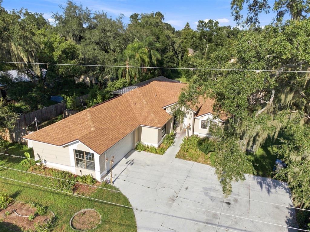 An aerial view of a single-story house with a brown shingled roof and concrete driveway — 207 LIMONA ROAD, BRANDON, FL