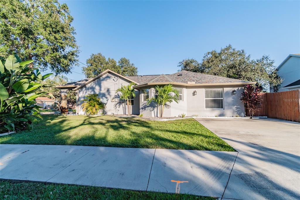 A single-story house with a gray exterior, a concrete driveway, and a front lawn — 3208 W NAPOLEON AVENUE, TAMPA, FL