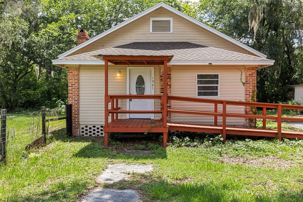A single-story house with beige siding, a red porch, and a wheelchair ramp — 1921 NE 8TH ROAD, OCALA, FL