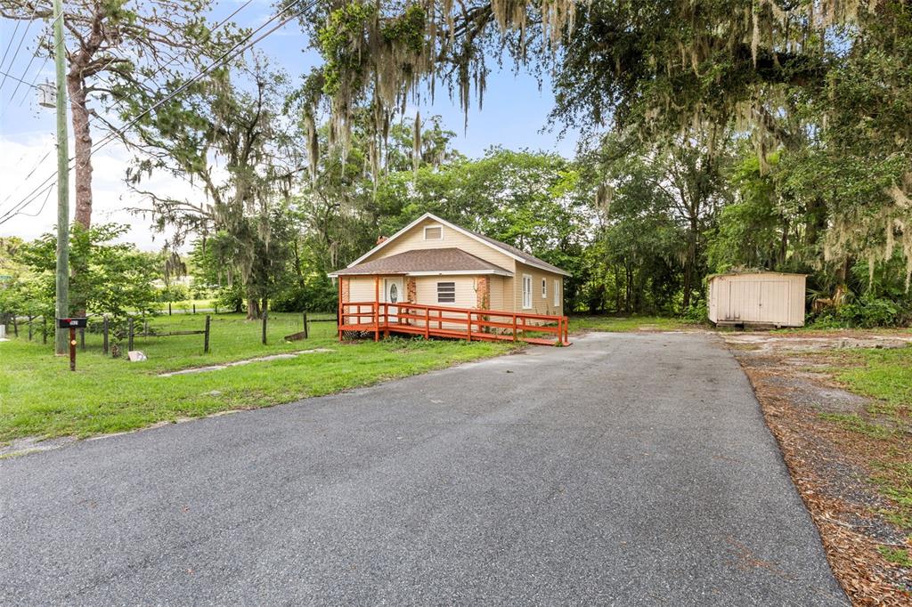 A tan house with a red wheelchair ramp sits on a lot with a driveway — 1921 NE 8TH ROAD, OCALA, FL