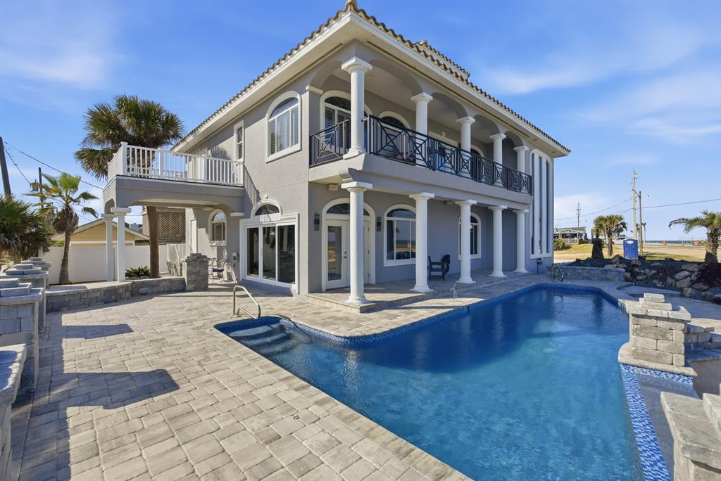 A two-story gray house with a swimming pool, stone patio, and white columns — 100 SANDPIPER RIDGE DRIVE, ORMOND BEACH, FL