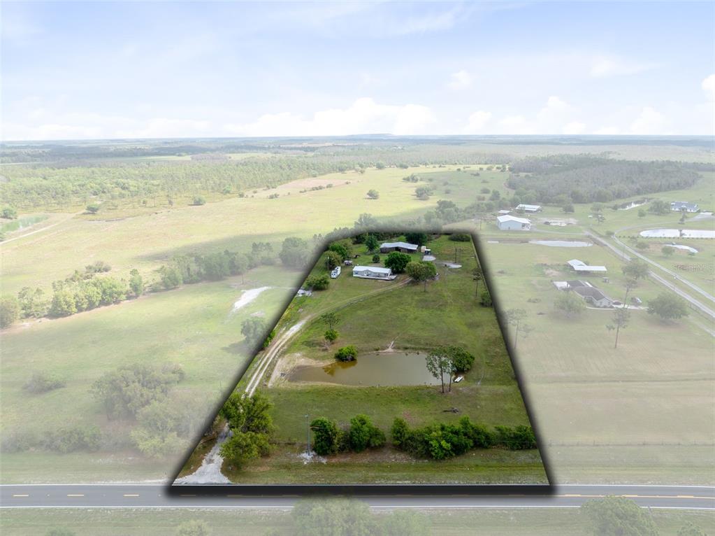 An aerial view shows a single-story house with a metal roof and a large wooden deck — 3591 N CANOE CREEK ROAD, KENANSVILLE, FL