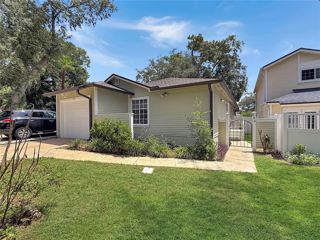 A single-story house with light green siding, a garage, and a gated walkway — 506 HARVARD PLACE, APOPKA, FL