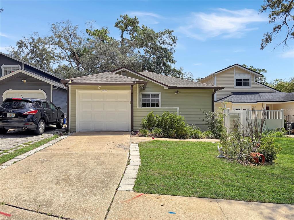 A light green single-story house with a white garage door and a concrete driveway — 506 HARVARD PLACE, APOPKA, FL