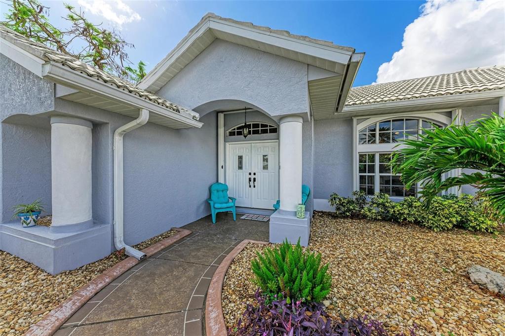 The exterior of a light blue house features a covered entryway with white columns — 316 ROSELING CIRCLE, VENICE, FL