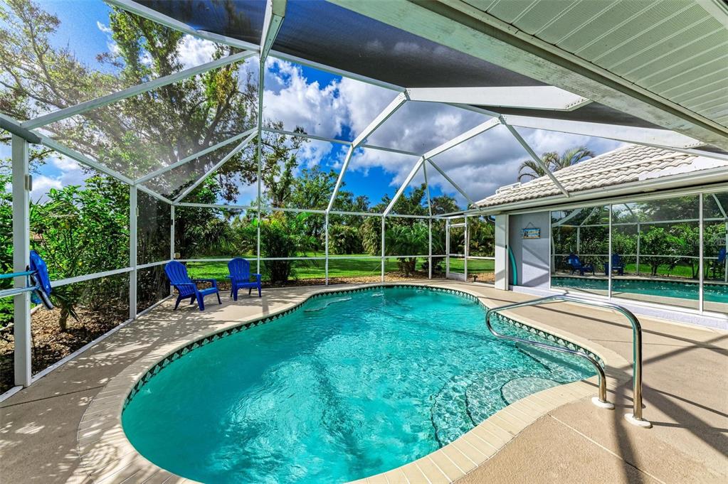 A screened-in swimming pool with a concrete deck and two blue chairs under a lanai — 316 ROSELING CIRCLE, VENICE, FL