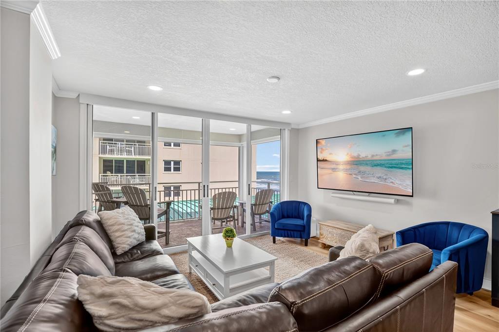 A living room features a brown sectional, two blue armchairs, and a balcony with ocean views — 4505 S ATLANTIC AVENUE UNIT 305, PONCE INLET, FL