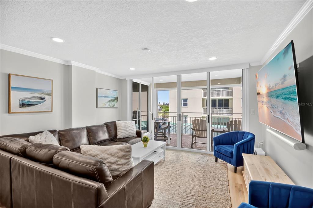 A living room features a brown leather sectional, blue armchairs, and a balcony with seating — 4505 S ATLANTIC AVENUE UNIT 305, PONCE INLET, FL