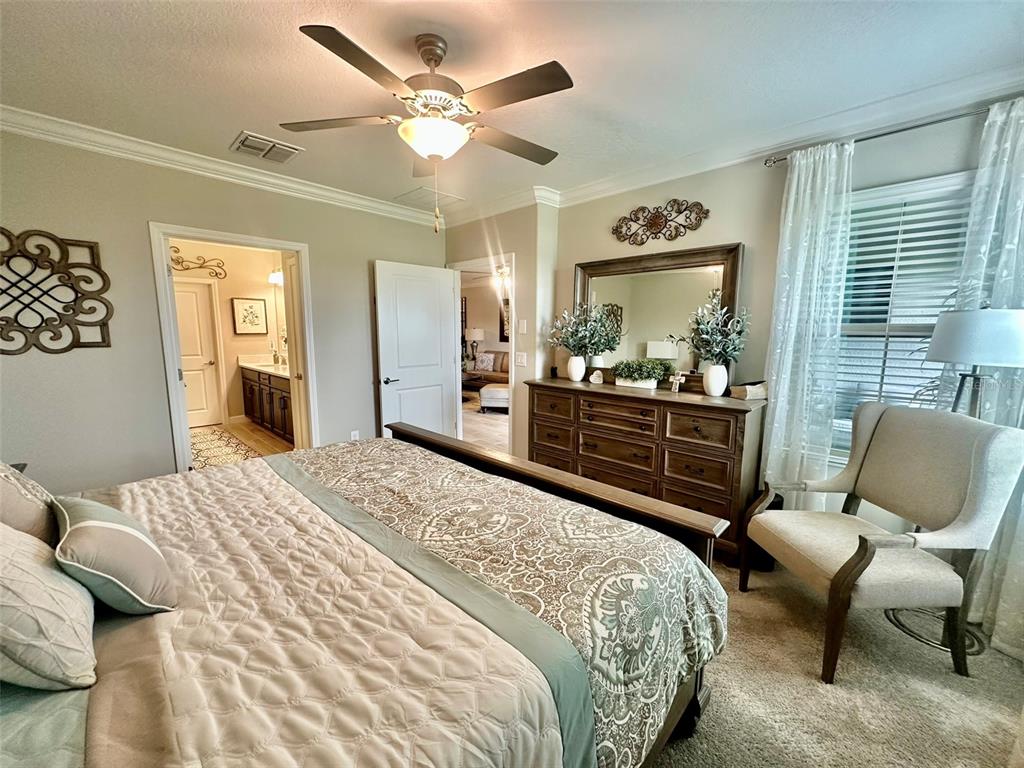A bedroom features a bed with patterned bedding, a wooden dresser with a mirror, and a chair — 10442 ECHO DOCK LOOP, SAN ANTONIO, FL