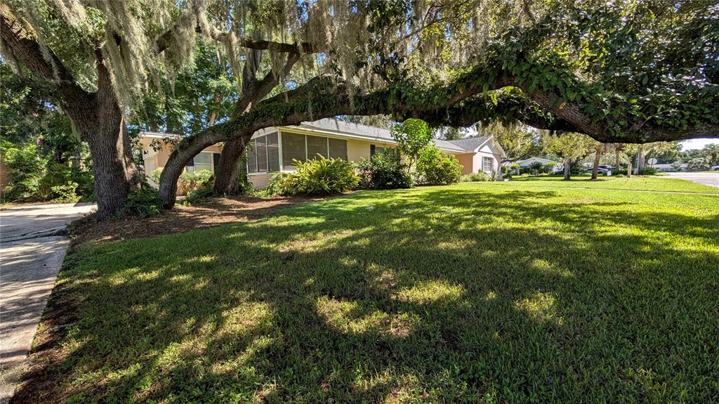 A single-story house with a light-colored exterior sits on a grassy lot with trees — 2469 BROADVUE AVENUE, EUSTIS, FL
