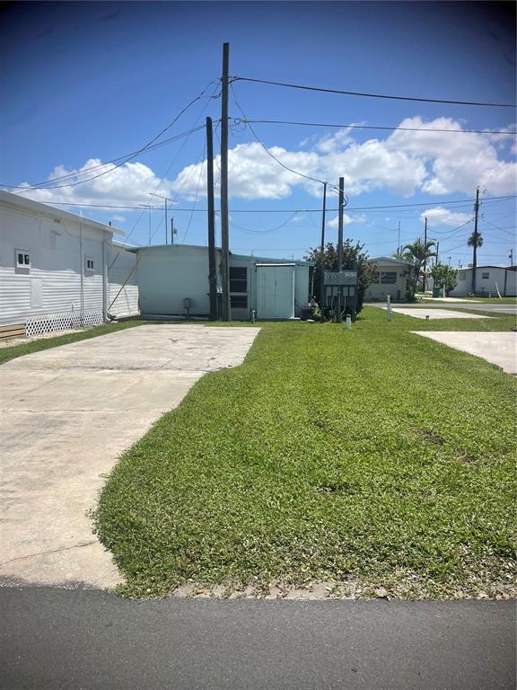 A concrete driveway leads to a light blue mobile home under a bright blue sky — 9 TENNESSEE STREET, PALMETTO, FL
