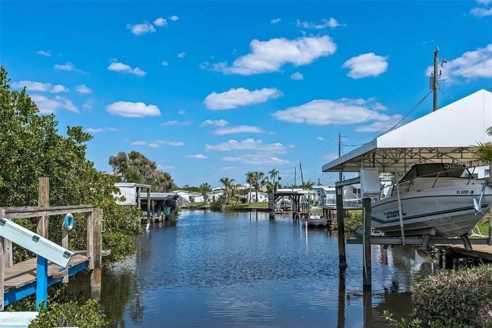 A boat sits under a covered dock on a canal lined with trees and homes — 9 TENNESSEE STREET, PALMETTO, FL