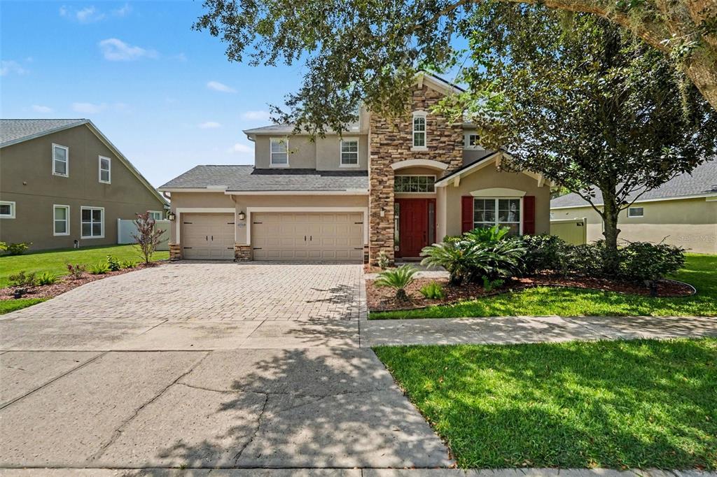 A two-story suburban house with a stone facade, red front door, and paved driveway — 2605 RED FERN DRIVE, DOVER, FL
